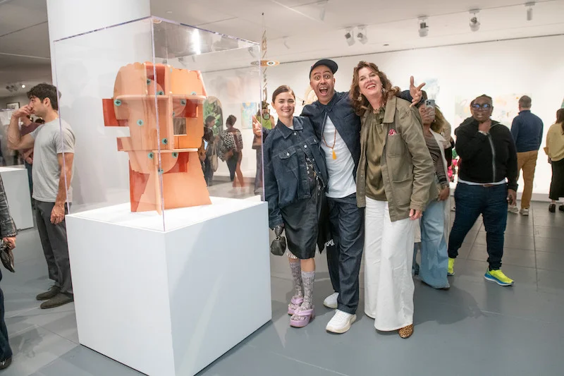 Three people pose for a photo in an art gallery