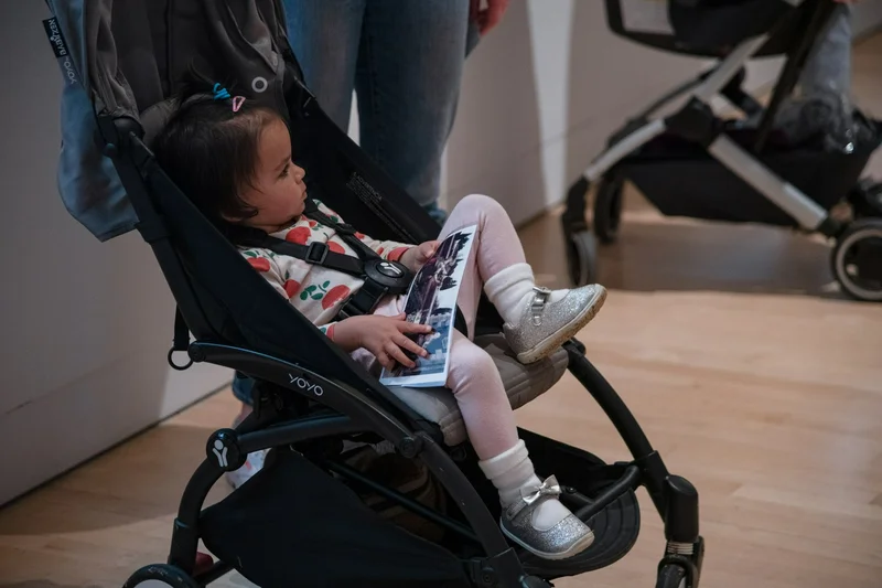 A child sits in a stroller holding a piece of paper