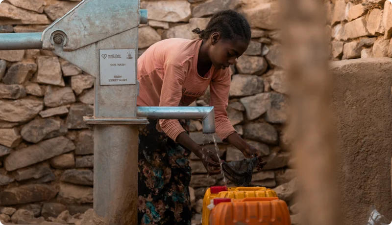 A young woman filling a jerry can with water.
