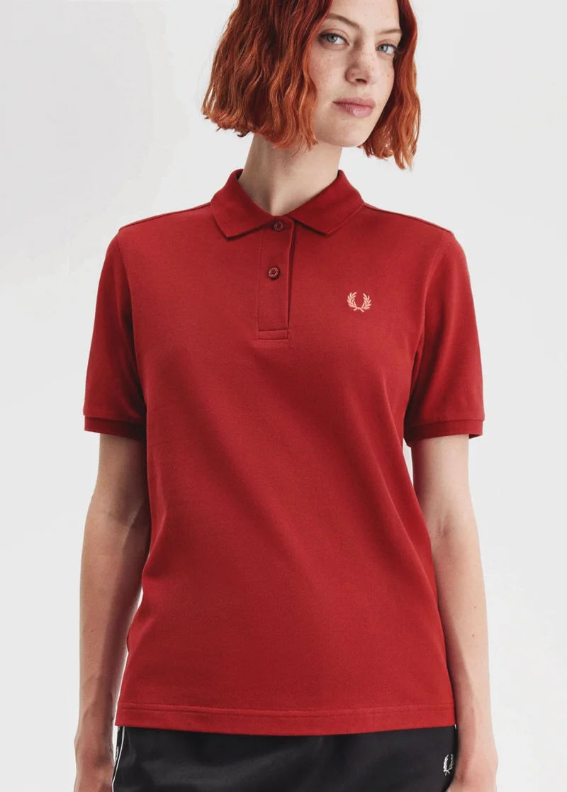 A white female model wearing a Fred Perry Shirt in Burnt Red / Putty Pink