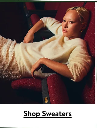A woman wearing an off-white cashmere sweater with a feathery skirt.