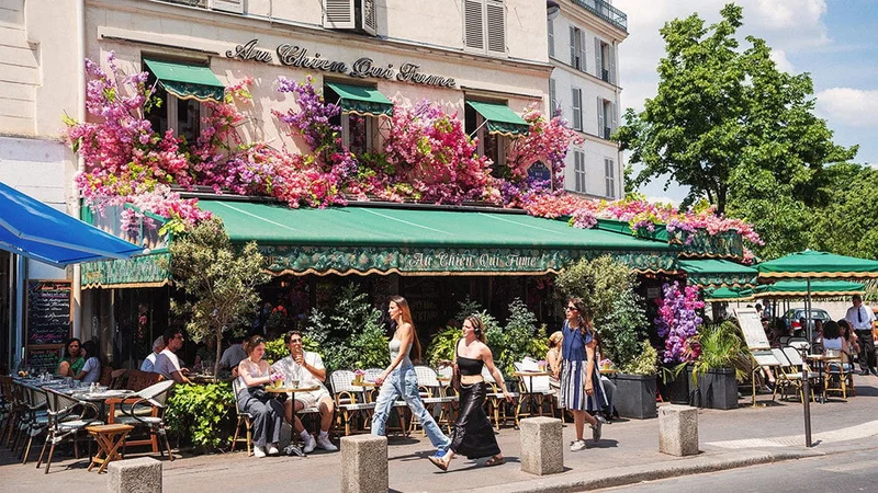 Image description: People walking past a restaurant with flowers in Paris during spring