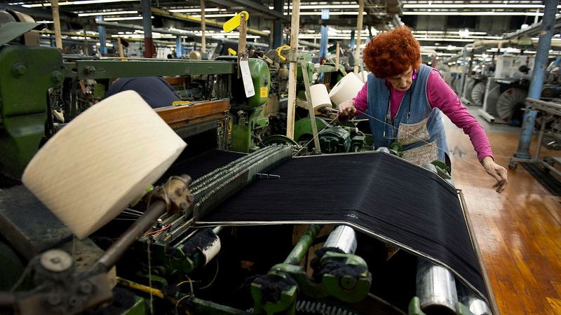 Employee Mildred Bolen, 77, monitors an X3 Draper Corp. shuttle loom at the International Textile Group Inc. Cone Denim White Oak plant in Greensboro, North Carolina, U.S., on Thursday, March 1, 2012. Gross domestic product climbed at a 2.2 percent annual rate in the first quarter after a 3 percent pace in the previous three months, according to the Commerce Department. Photographer: Davis Turner/Bloomberg via Getty Images