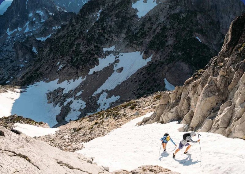 Two hikers ascend a snowy mountain gulley.