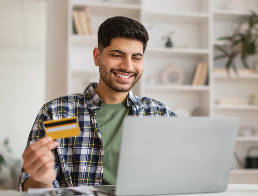 Person a sitting at a computer with a credit card in their hand