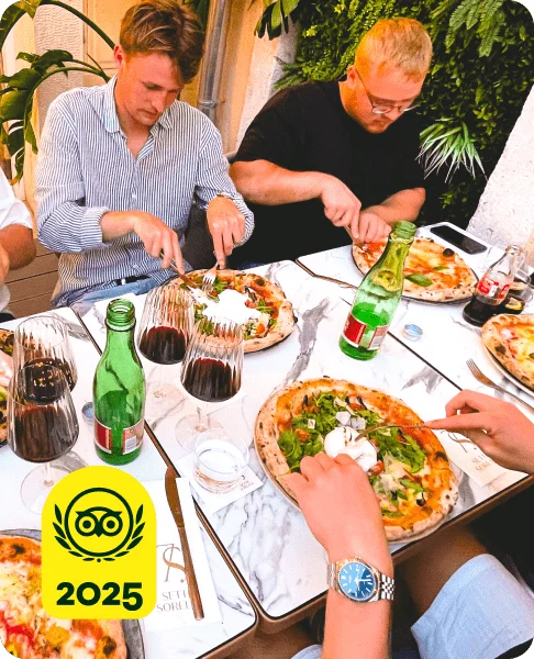 Image Description: Three people at a table eating pizza. A yellow 2025 Travelers’ Choice Awards Best of the Best badge is on the bottom left corner of the image.