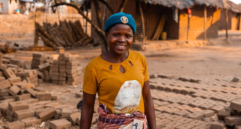 Mary smiles in front of the house her and her family are constructing.