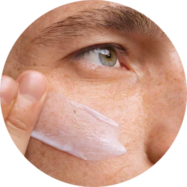 Close up of person swiping moisturizer onto cheek.