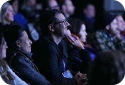 People in a dark theater at a Festival screening smiling and enjoying themselves.