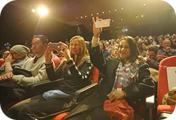 The audience at a Festival screening – in the front row, two women hold up their phones taking a picture.