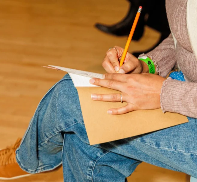 A close-up of a woman writing with pencil
