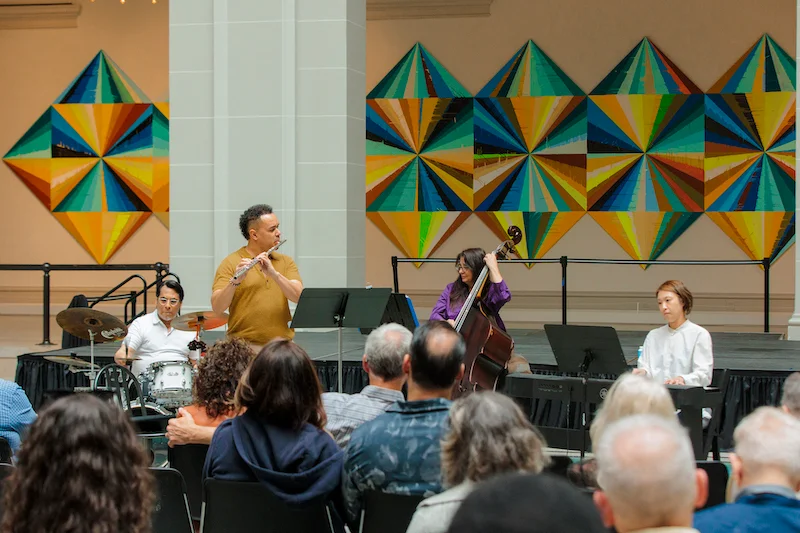 An orchestra plays in an art gallery to an audience