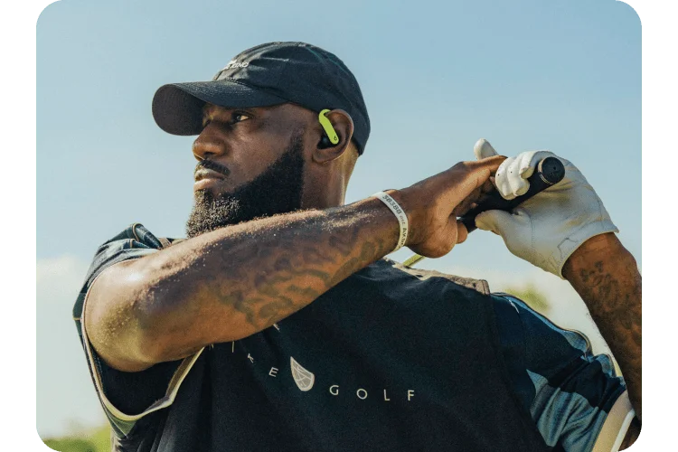 LeBron James swinging a golf club wearing the special-edition Nike Powerbeats Pro 2 earbuds.