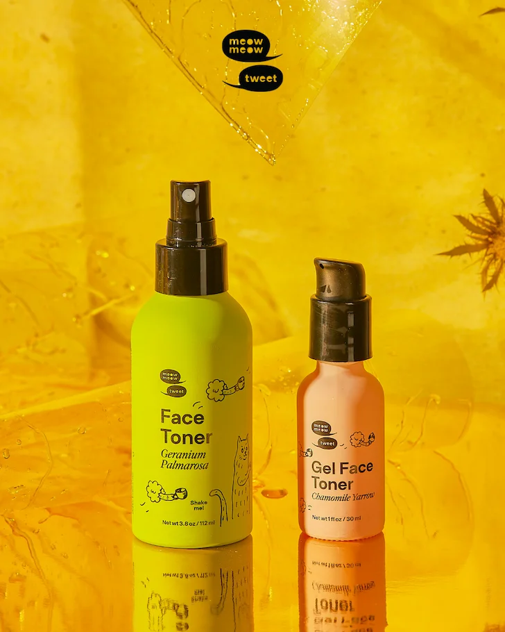 Two bottles, one green and one pink, stand against a reflective yellow background.