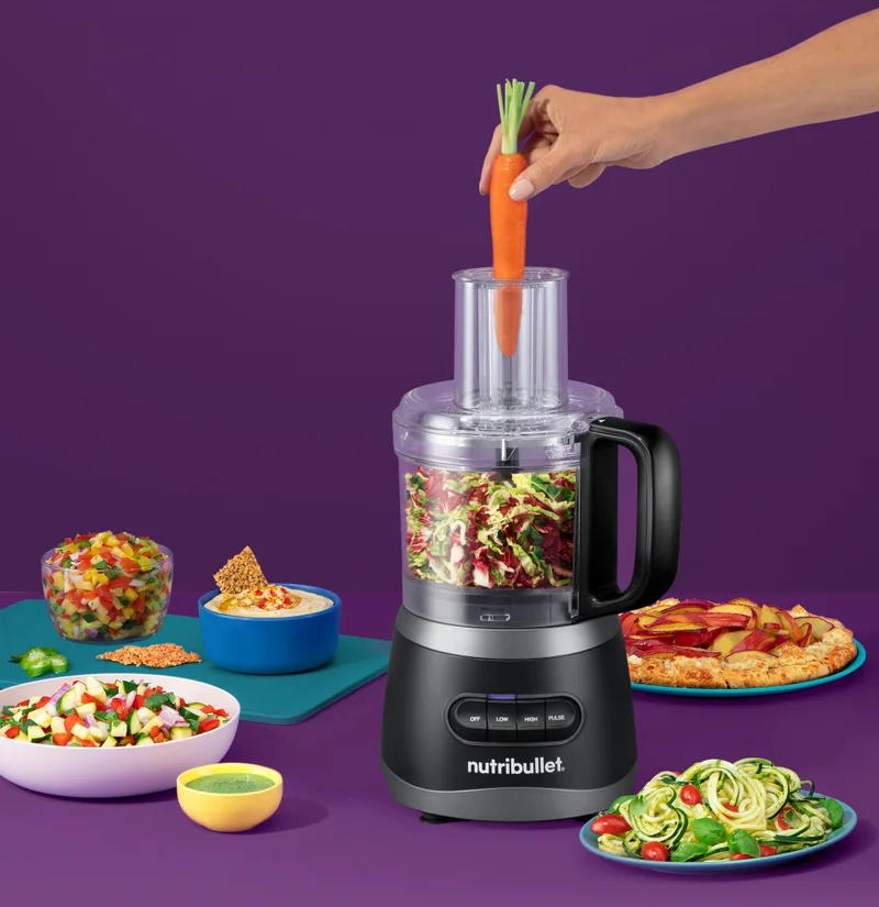 A person adding a carrot into a nutribullet Food processor