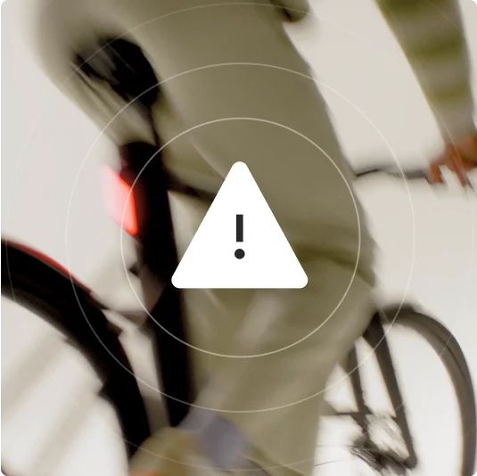 A graphic. A white warning triangle within concentric rings white resembling a radar screen. The background is a silhouetted figure on a bike against a dark sky.