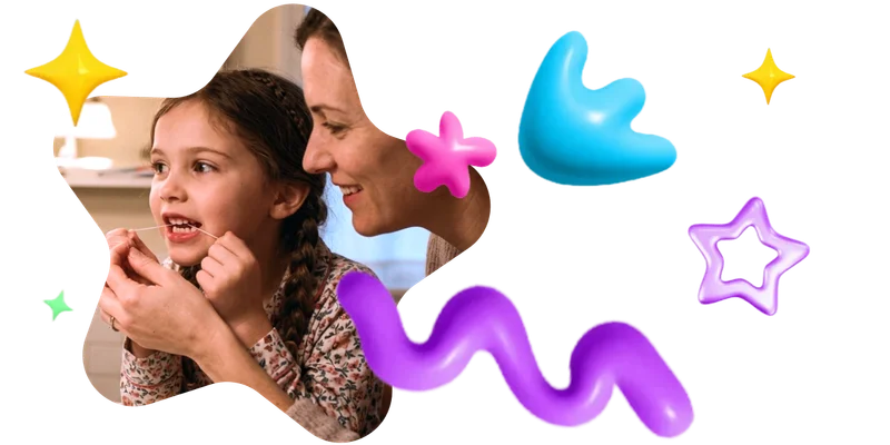 A mother helping her young daughter floss.