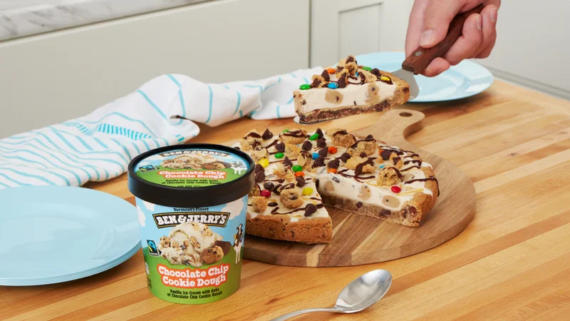 Pint of Ben & Jerry's Chocolate Chip Cookie Dough ice cream next to a cookie pizza topped with ice cream and toppings.