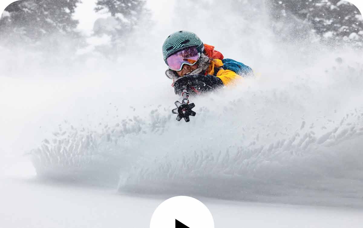 A skier kicks up a wave of snow before them and only their goggles and helmet are visible.