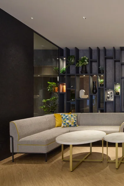 Modern hotel living room with sofa, chair, and floor lamp.