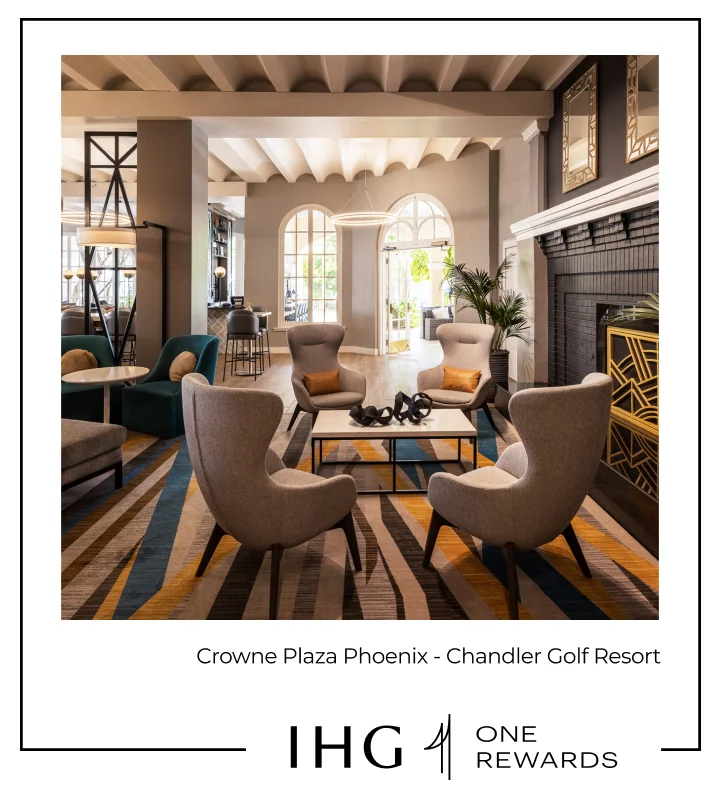 A well lit upscale hotel lounge with chairs by a fireplace.