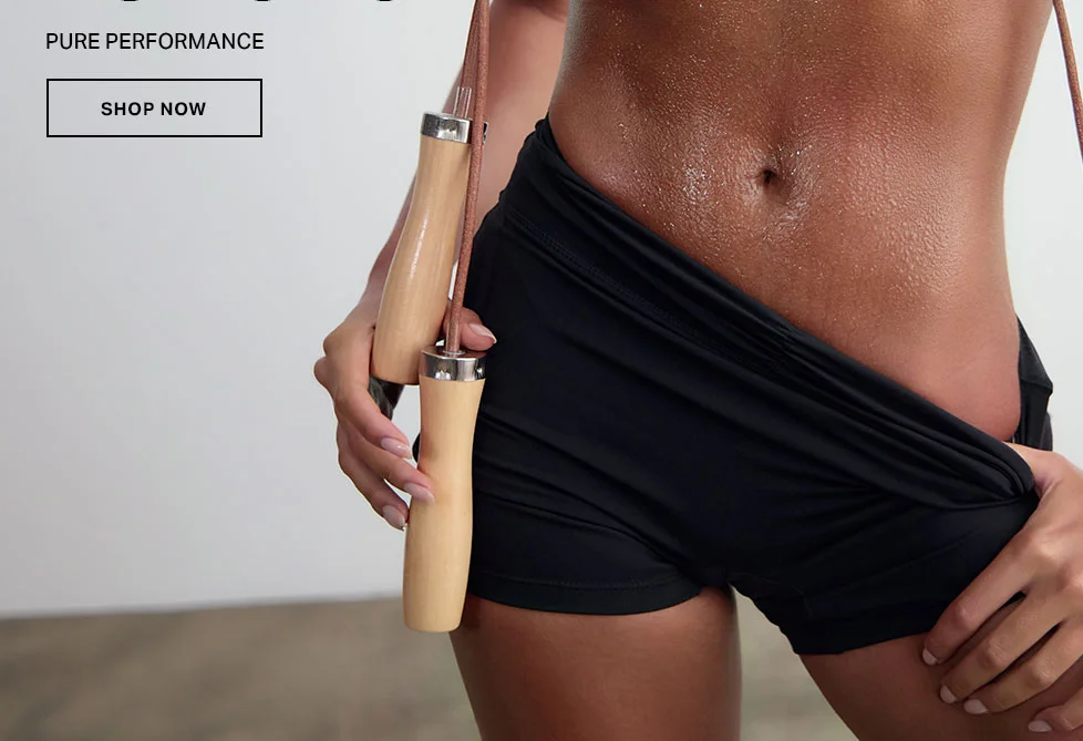 Sweaty athlete holds wooden jump rope, wearing black athletic shorts for peak fitness performance.