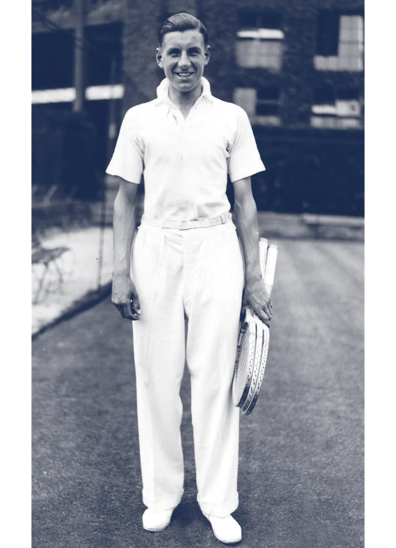 Archive image of Fred Perry himself, wearing the original Fred Perry polo shirt on a tennis court, smiling and holding tennis rackets
