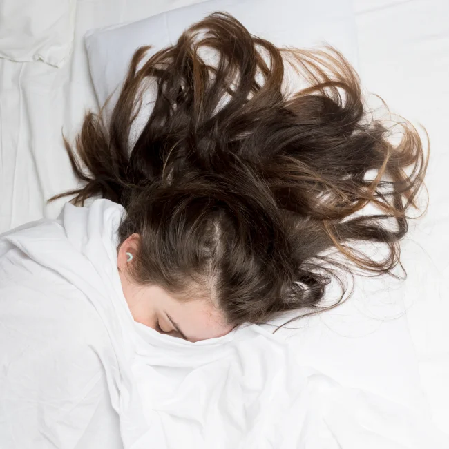 A sleeping woman wearing a pair of Loop Quiets.