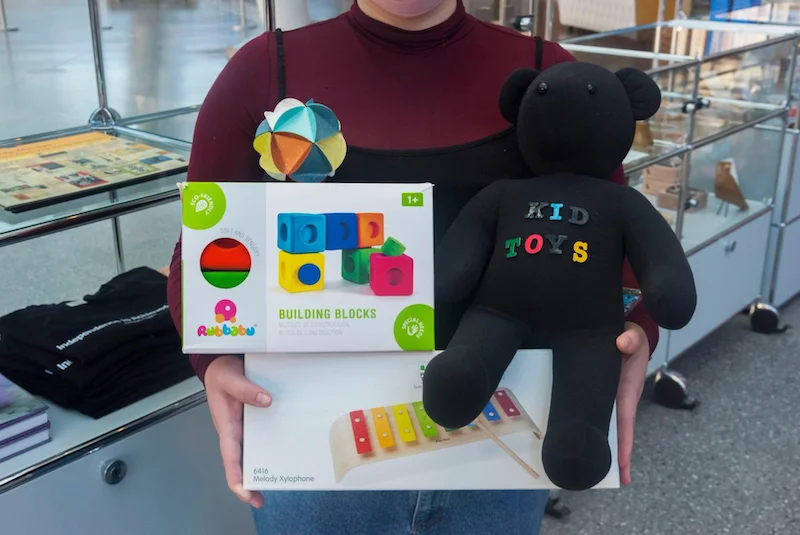 A person holding boxes of toys and a stuffed bear