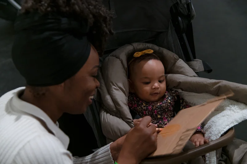 A woman and child in a stroller looking at art