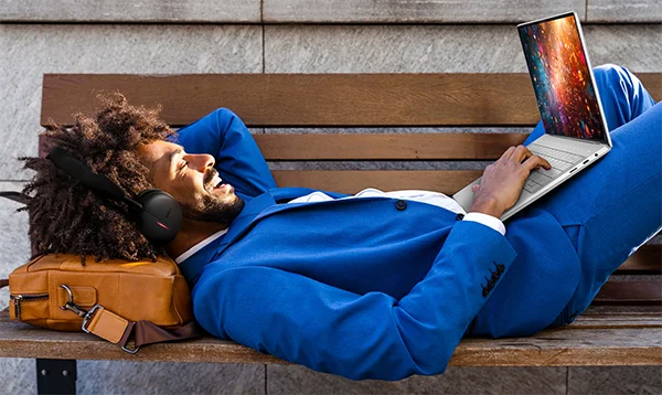 Happy Businessman with Headphones Lying Down Taking Call from Bench