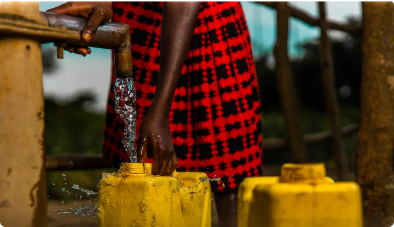 A young woman filling a jerry can with water.