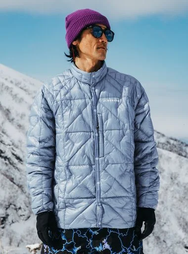 The Men's Burton [ak] Baker Ultralight Down Jacket in blue on a model in the mountains