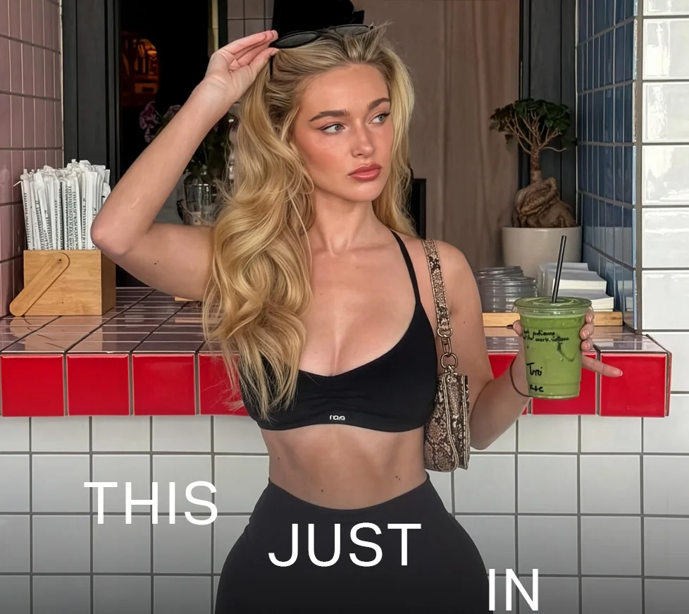 Blonde woman in black activewear holding a green smoothie at a cafe counter. Discover our new arrivals in fitness apparel and healthy living essentials!