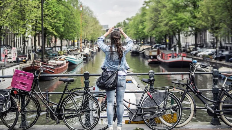 A girl takes a photo of a canal in Amsterdam.