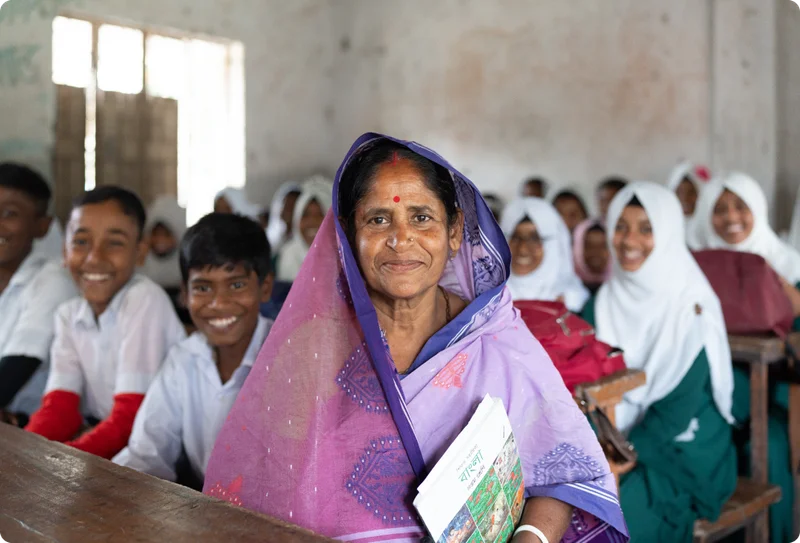 A high school teacher named Kabita sits with her students in their Bangladeshi school.