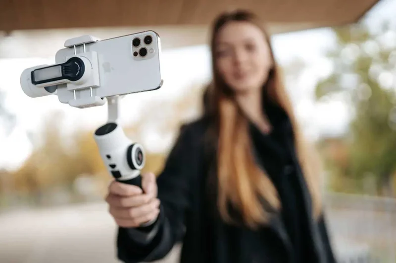Image of woman holding a zhiyn gimbal with a phone mounted to it.