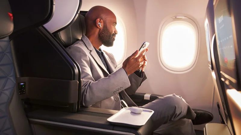 A Delta customer sits in the First Class cabin, holding his phone.