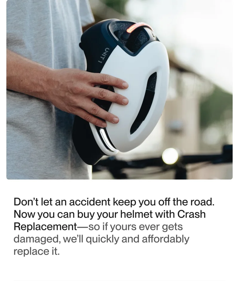 Rider holding the Unit 1 helmet, showcasing the sleek design and crash replacement feature.
