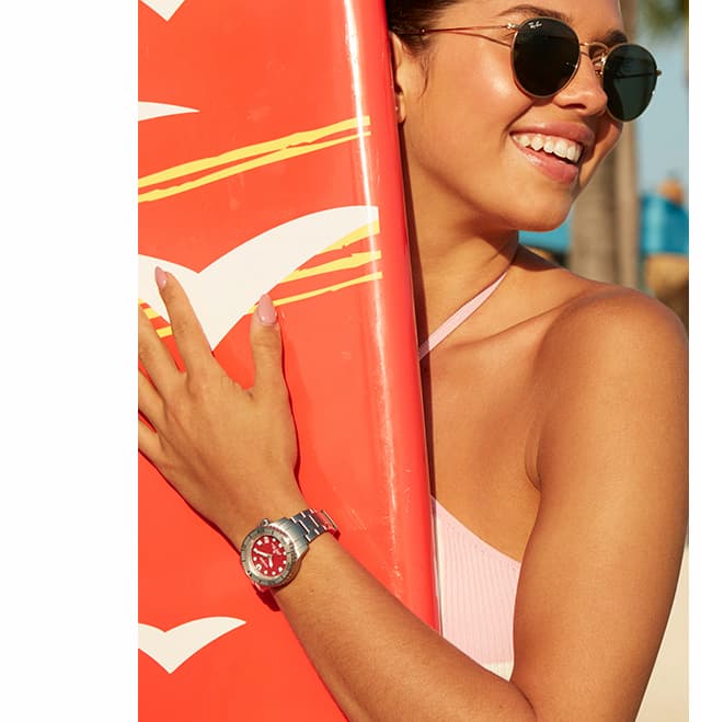 Woman holding an orange surfboard and wearing a Promaster Dive