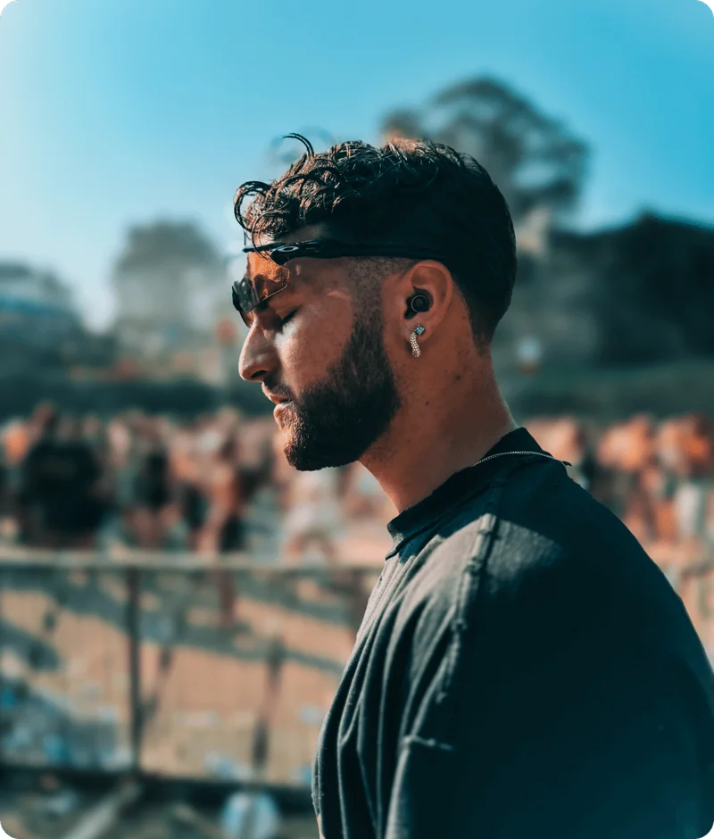 Man wearing Loop x Tomorrowland earplugs at an outdoor party.