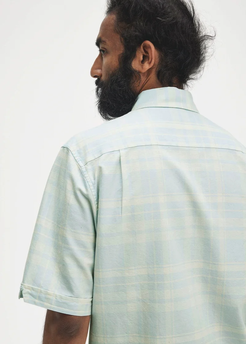 Male model wearing a light blue tartan short sleeved shirt
