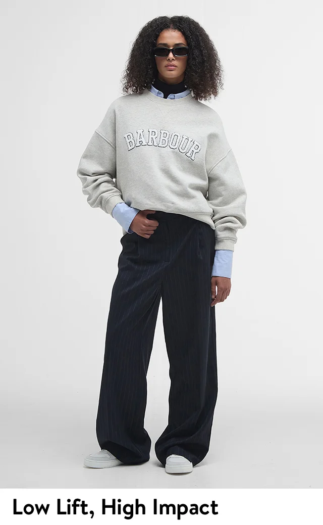A woman wearing a grey graphic sweatshirt with pinstripe trousers.