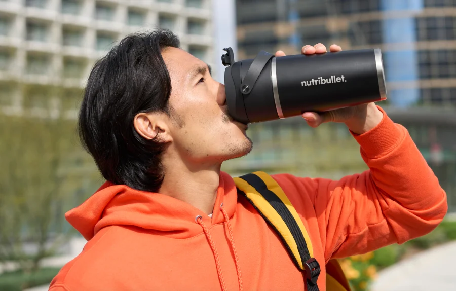 A portable nutribullet blender with fruits and ice inside.