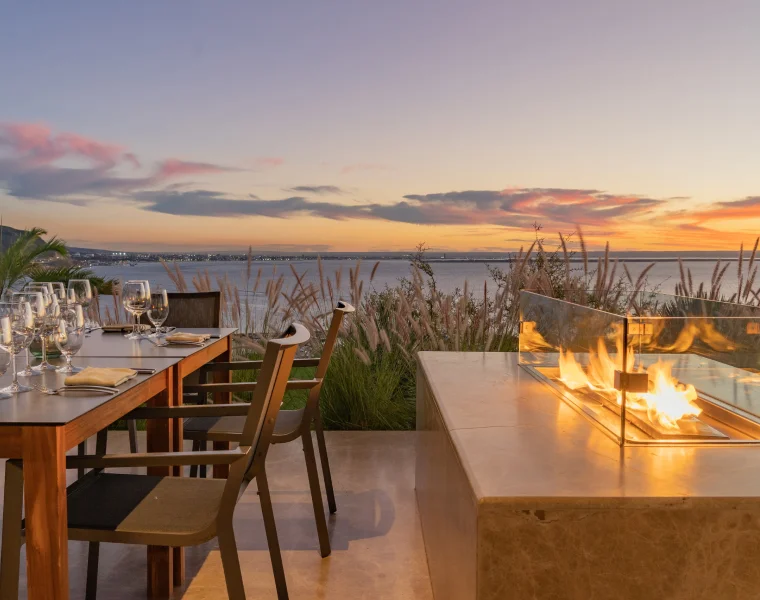Sunset in an outdoor dining area overlooking the water with a fire pit