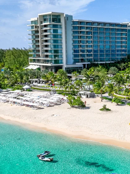 Two boats on a sparkling blue shore with a beachfront hotel.
