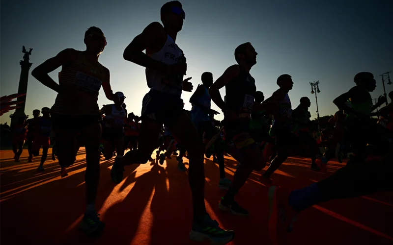 Several people shown in silhouette run a race.