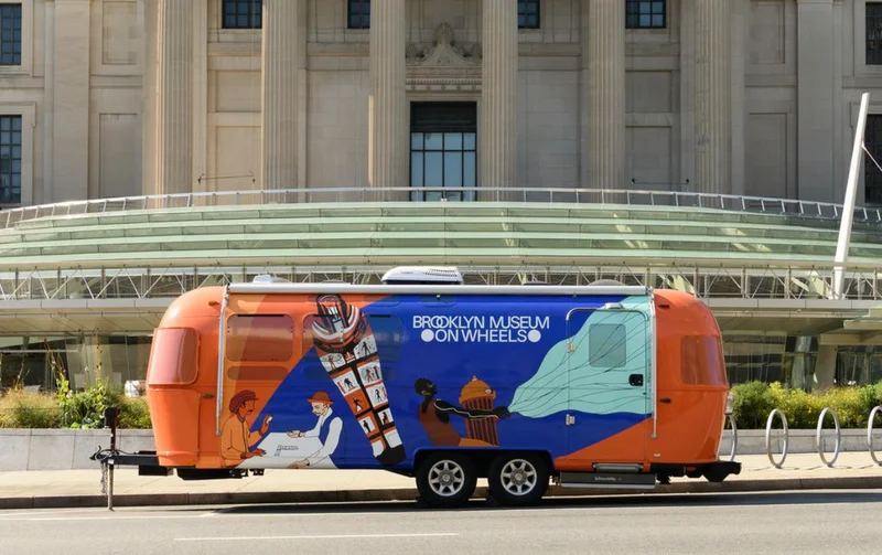 A blue-and-orange trailer reading "Brooklyn Museum on Wheels"