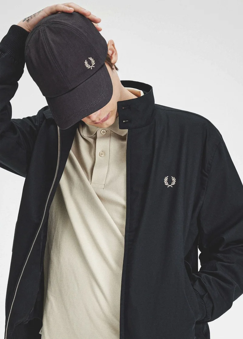 Man wearing Black Harrington Jacket, black cap and Oatmeal coloured Fred Perry Shirt