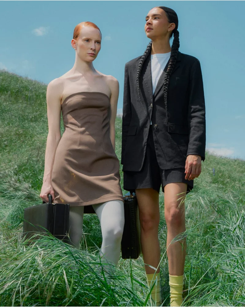 [Editorial Image] 2 Models holding suitcases in field of grass